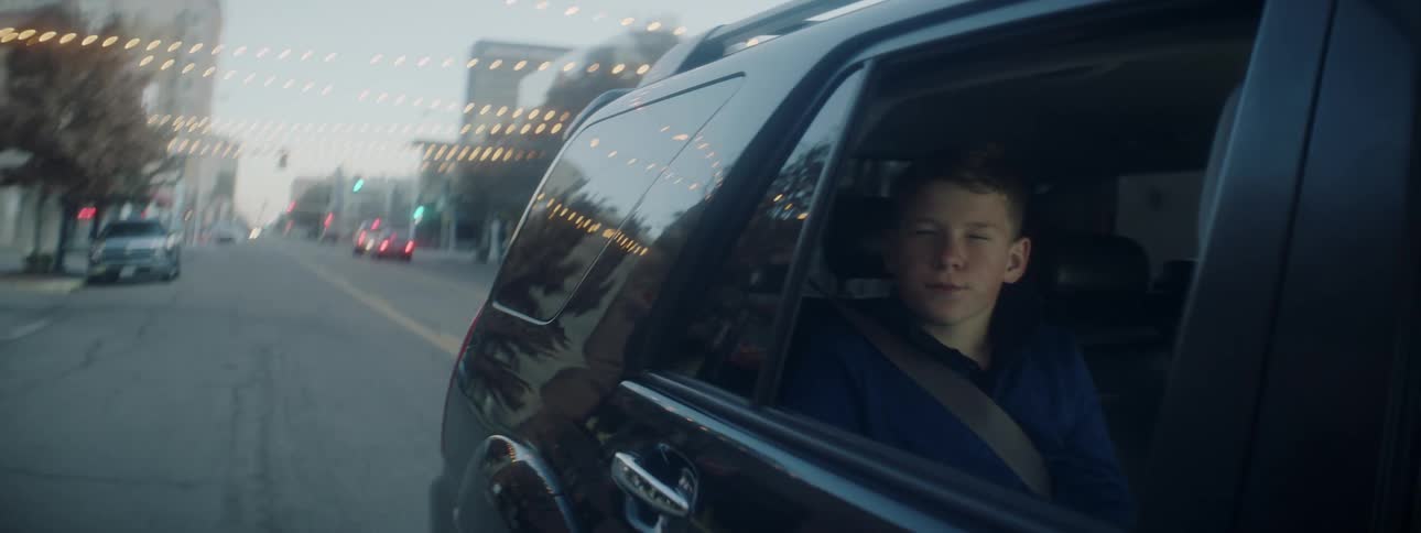 Boy looking out window of car driving down city street