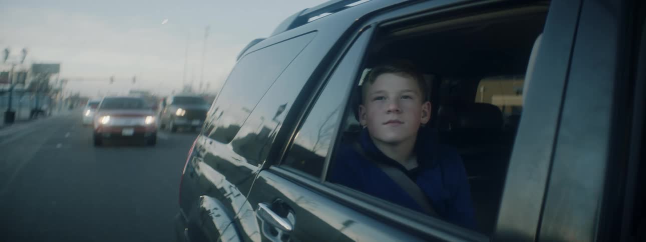 Boy looks out the side window of a moving car