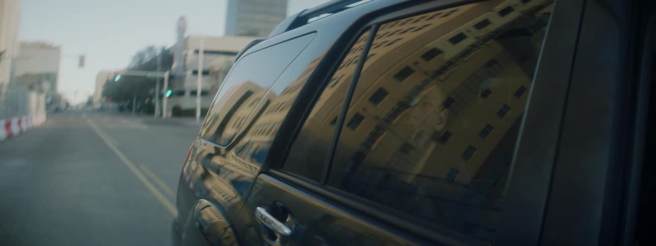 A young boy looks out of the passenger window of a vehicle to the passing cityscape