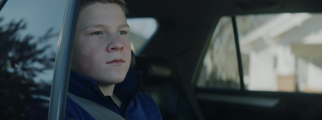 A boy sitting in the backseat of a car with his seatbelt on