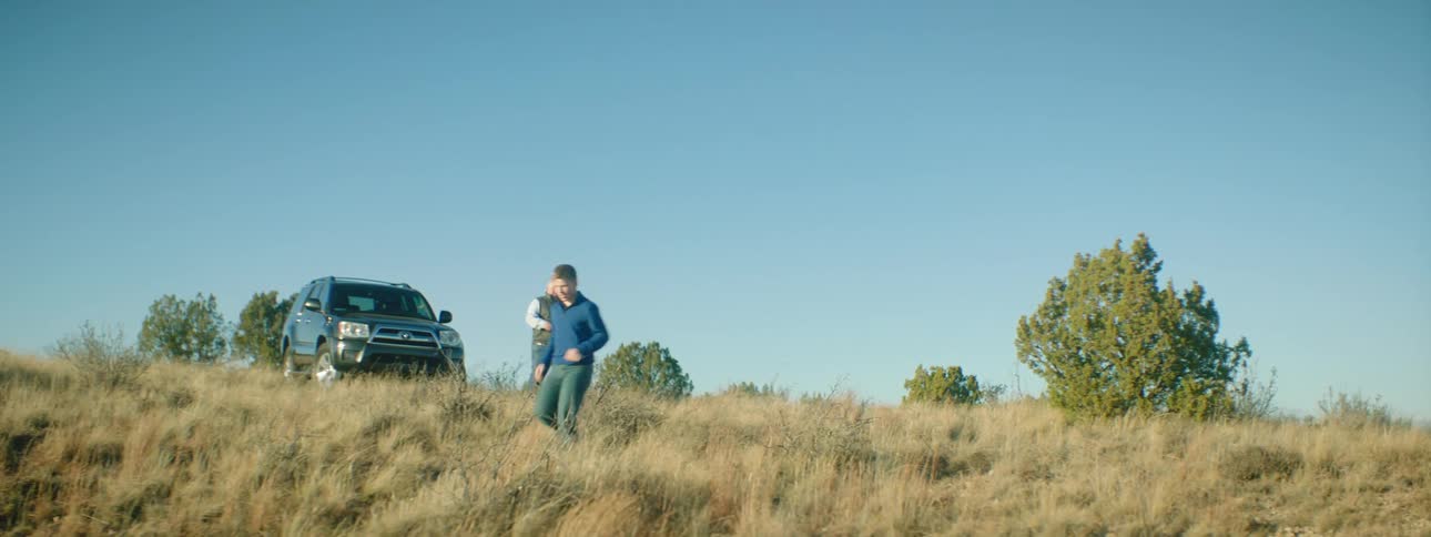 Two men get out of a vehicle parked on top of a hill and run down it