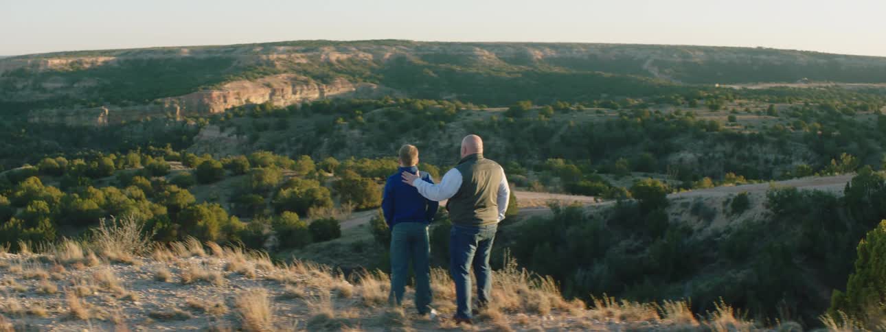 A father and son stand and look at the landscape