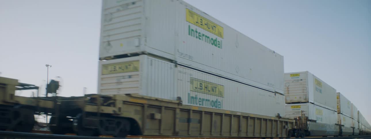 A freight train carrying shipping containers with the sky in the background