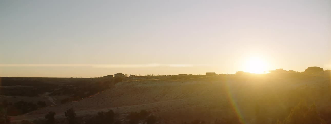 A rural area with trees with the sunset in the background