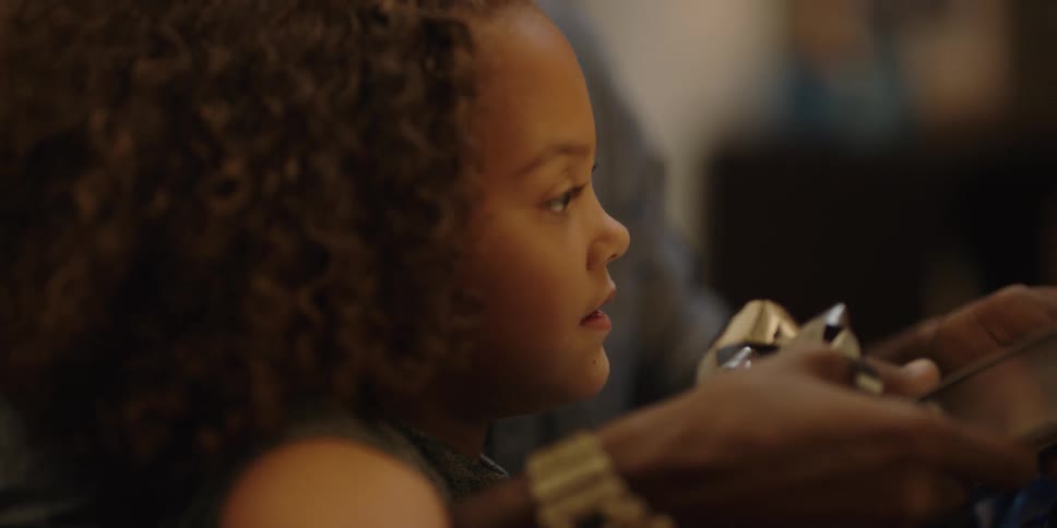 Young girl watching father open present