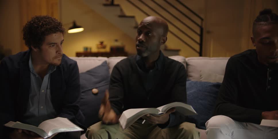 Men sitting on a couch talking and holding bibles