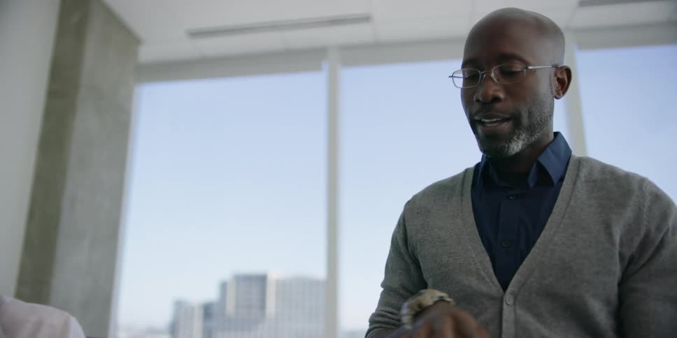 A man lifts a book and talks with coworkers