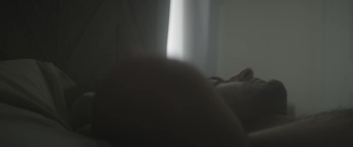 A man lying awake in bed during the day rolls over on his side