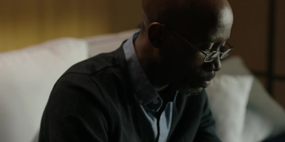Black man sitting on the sofa reads a book in the living room