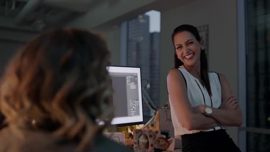 Female coworkers laughing and chatting at the office