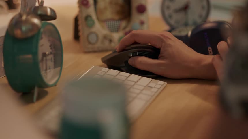 Near alarms clocks picture frame and white keyboard person uses black mouse sitting at desk