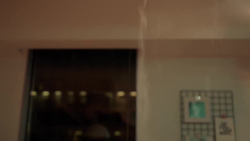 Woman sitting in the office at night notices dust coming from the ceiling
