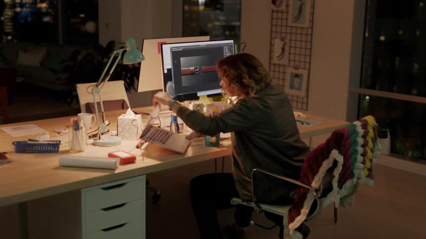 A woman runs to her desk and sits down and opens her laptop and looks at her computer monitor excitedly