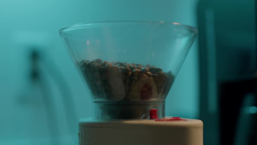 A woman pours coffee beans in to a grinder