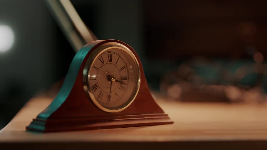 A golf club hits a clock off a wood desk