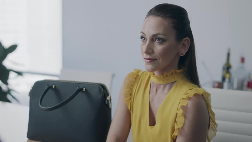 A well dressed woman turning and raising her head while sitting at a table
