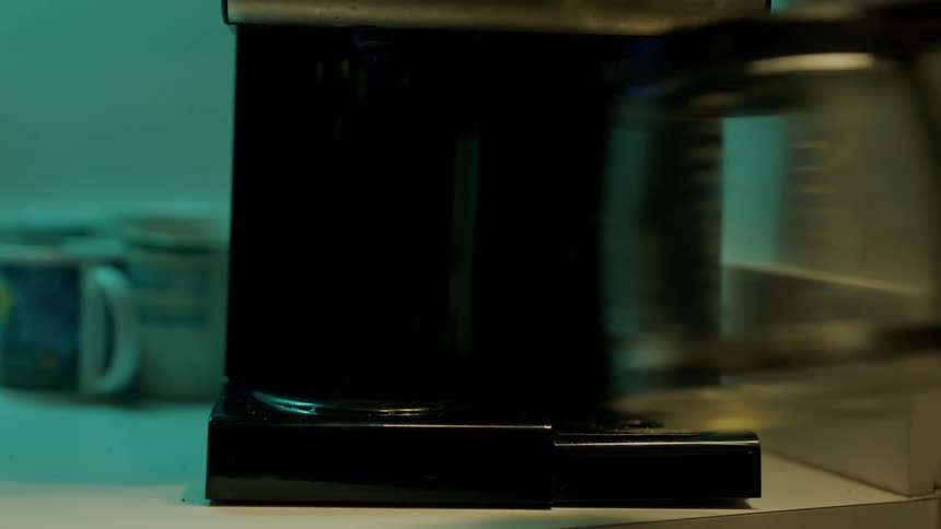 A woman puts a pot on the coffee machine