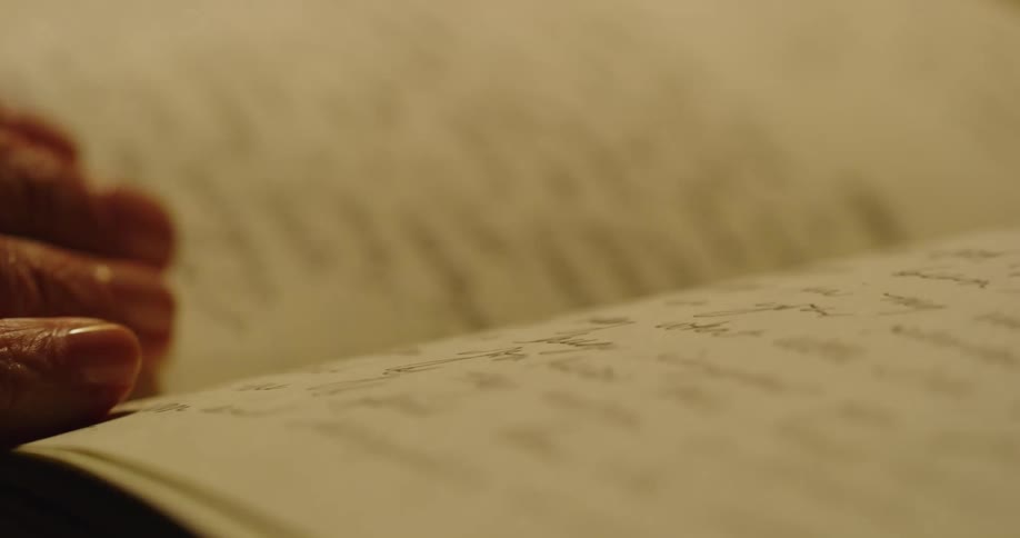 A person flips through pages of a hardcover notebook filled with notes