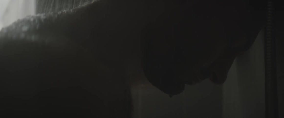 A man has his head down as water splashes onto his neck