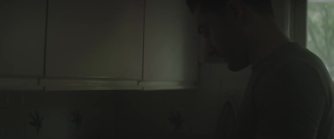 A man is talking as he looks down in a dark room