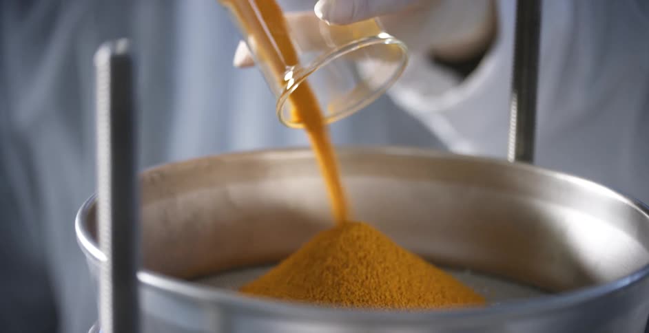 Doctor pours orange substance into a bowl in a lab