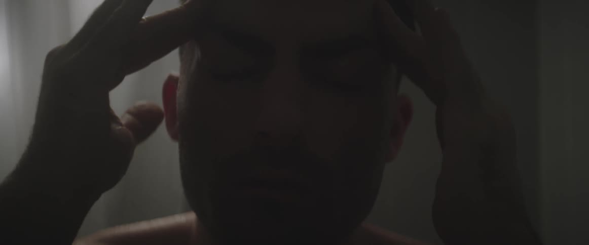 Man rubbing his temples while rocking and with his eyes closed