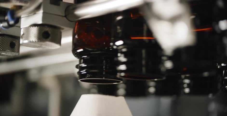 A machine dropping pills into brown glass buddies