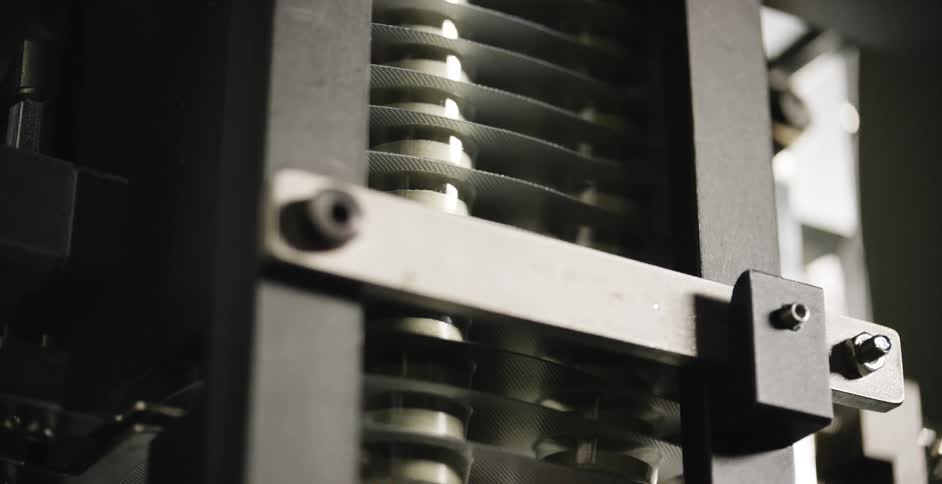 Wrapped pills drop out of a machine on an assembly line