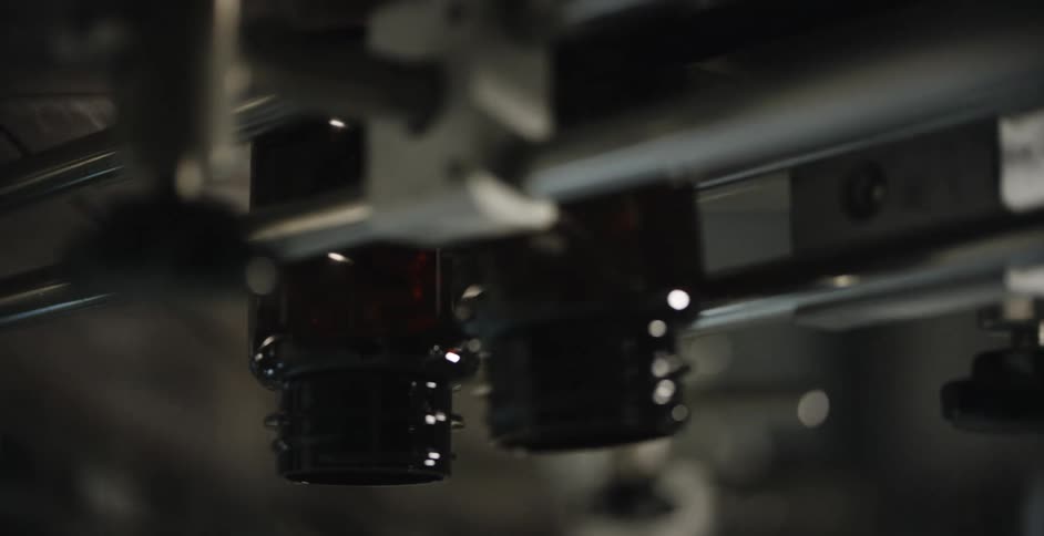 Glass vials move through a metal conveyor machine