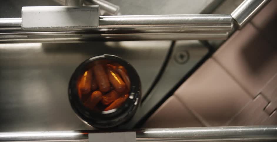 Bottle filled with pills rolling out of a conveyor belt
