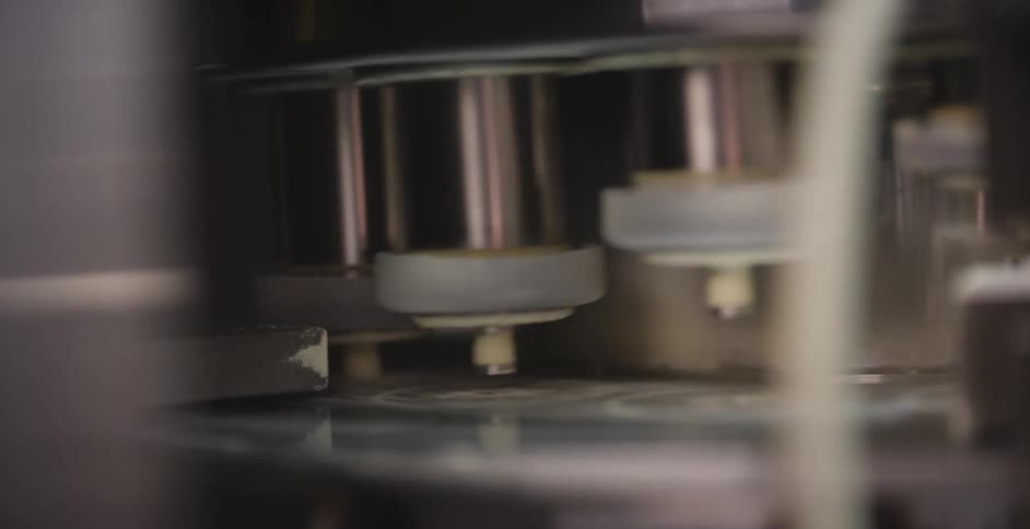 A machine turns with levers lifting and stamping and rising