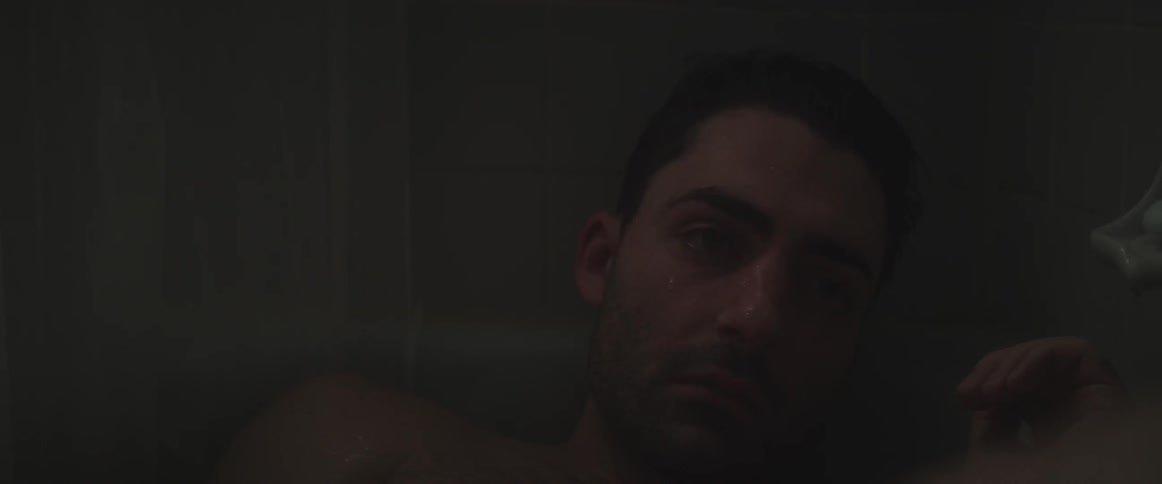 A shirtless man stares straight ahead