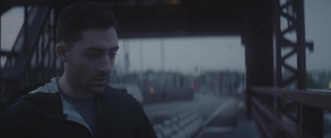 A man in a dark jacket walks under an overpass