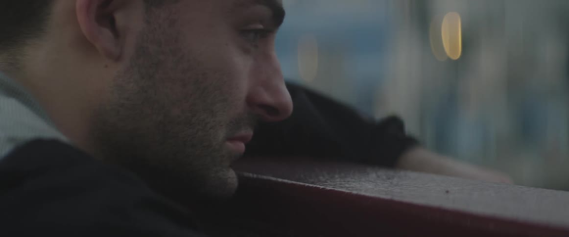 A sad looking man leans against a rail