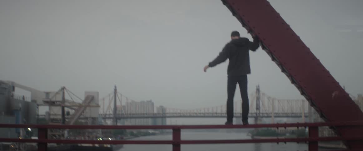 Man standing on the edge of a city bridge
