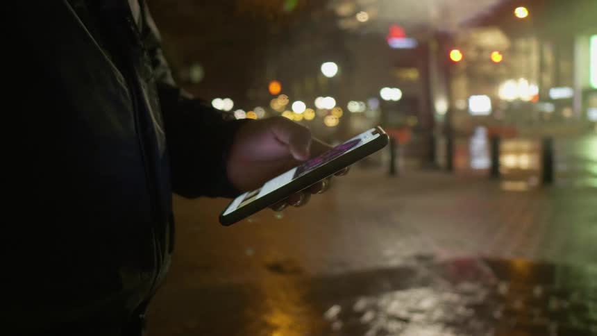 A man standing outside looking at a smart phone