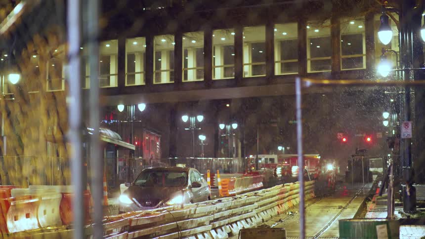 Cars drive slowly through a construction zone underneath an elevated walkway