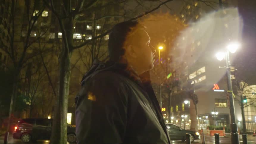 A man stands in a downtown area in winter and looks around