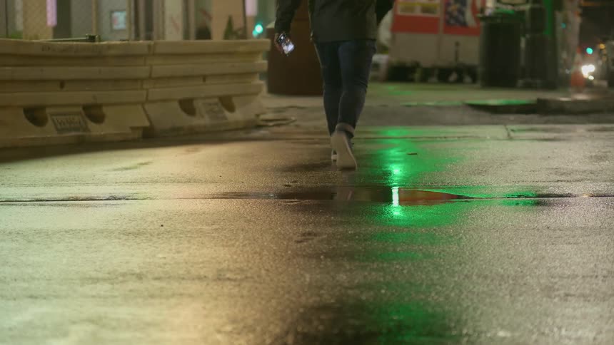 A teenager walks down a city street at night
