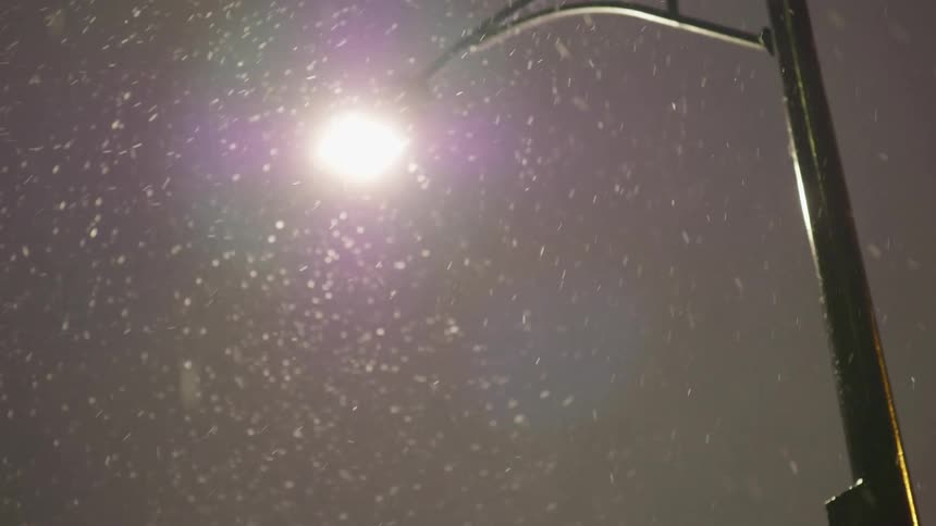 Snow falling in front of a street light