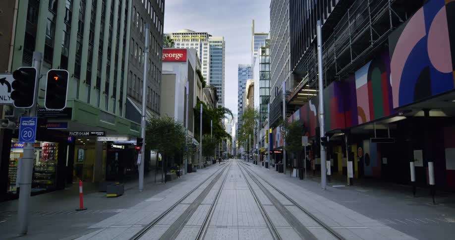 Trolley track run down the an empty city street with buildings and stores on both sides