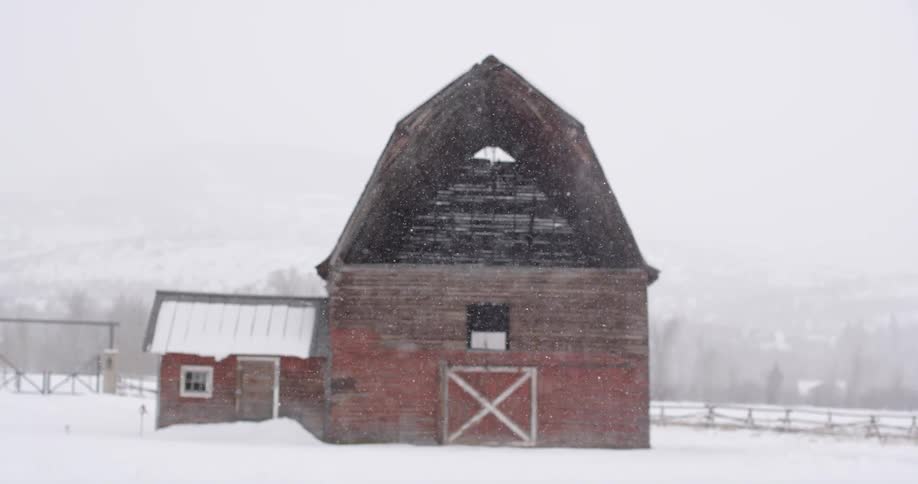 Snow falling over a barn