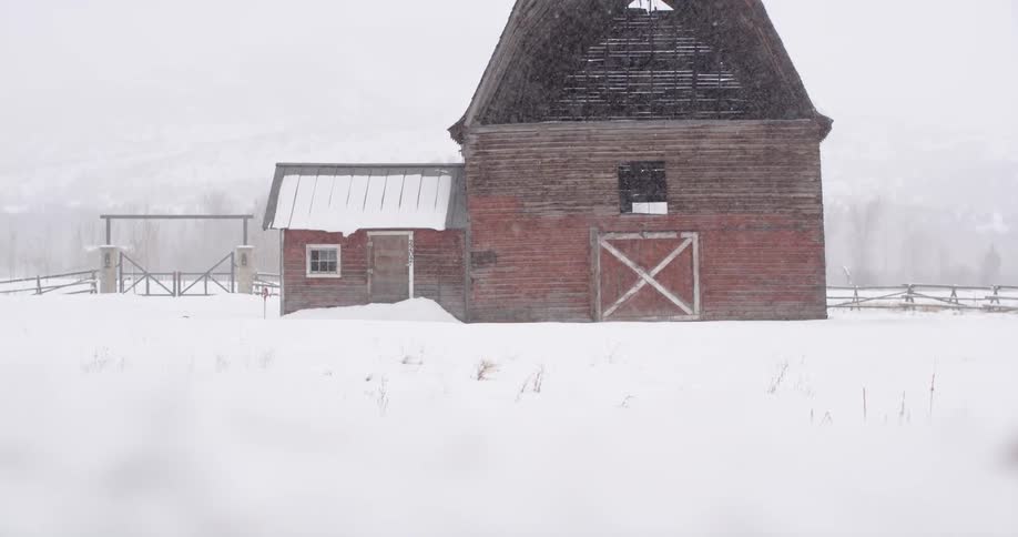 The snow falls over the farm house