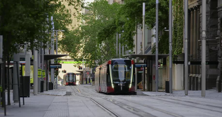 A trolley sits on street level tracks at a stop on an empty city street