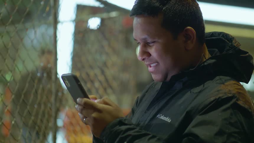 A man stands on the street in the snow and talks on his cell phone