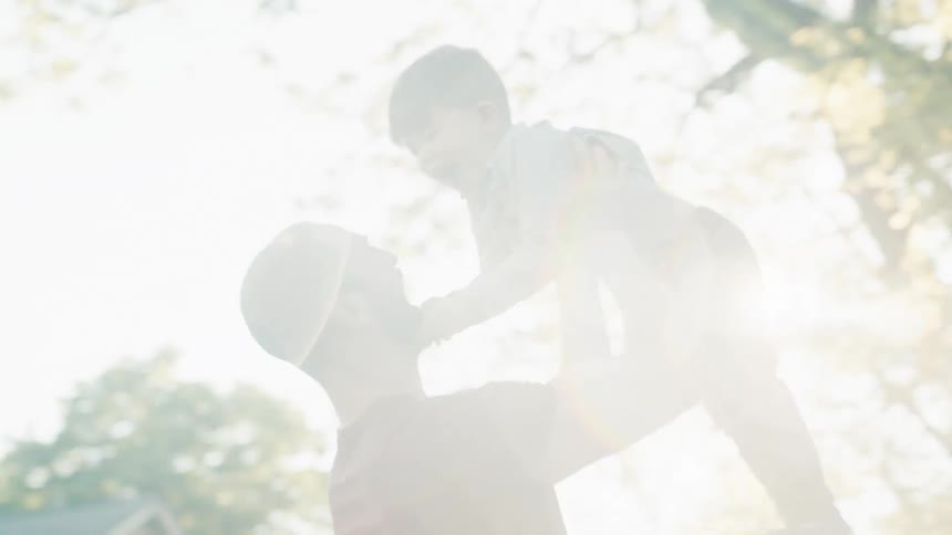 Father holds his son and laughs together in the garden