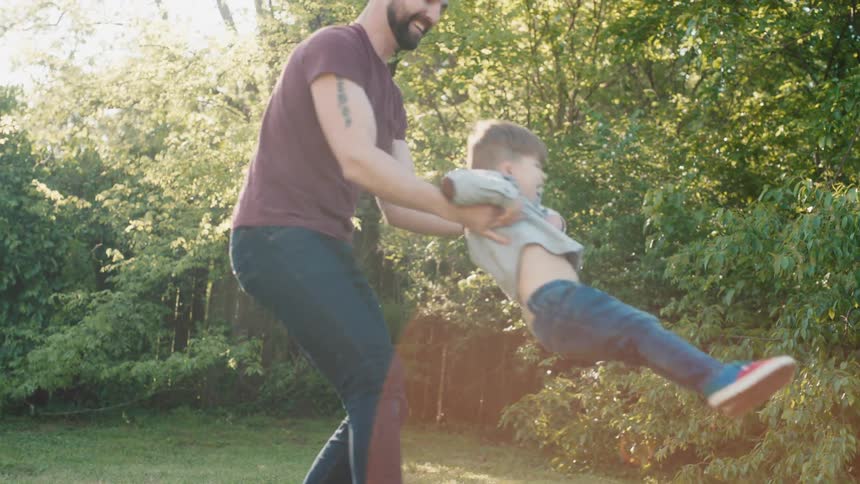 A father holds his son and spins him in a circle