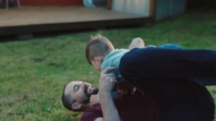 A father and his son play and laugh in a backyard