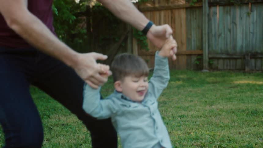Father and son play together on the grass in the backyard