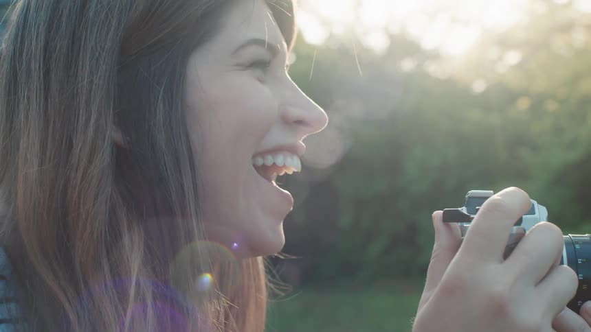 Woman takes photos with a camera on the backyard at sunset